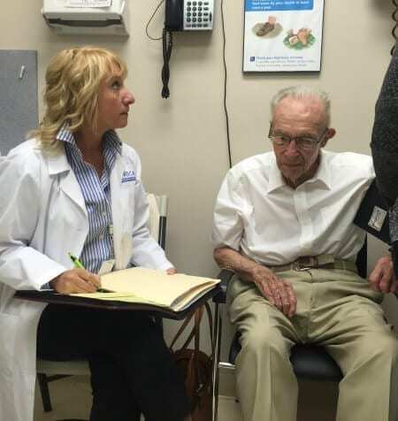 A doctor taking notes on an elderly patient