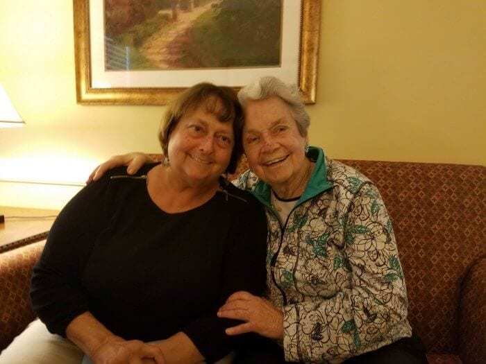 Two woman smiling together on a couch