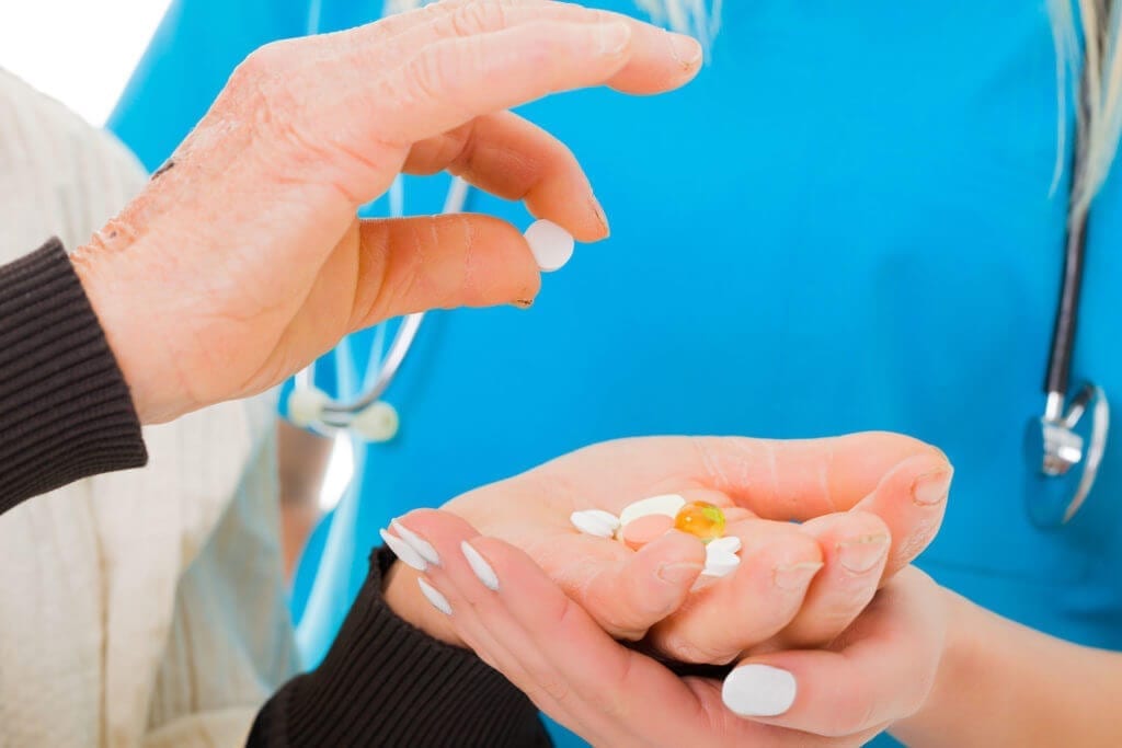 Older person putting pills in hand