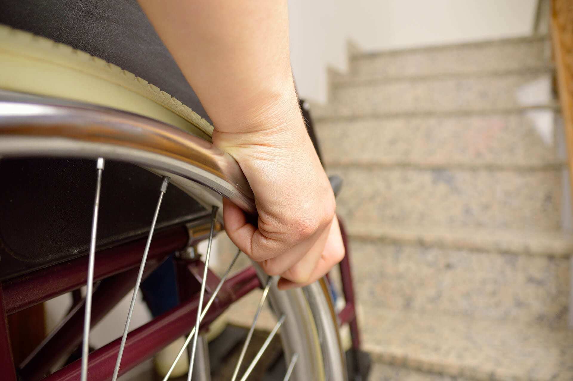 young disabled man in wheelchair in front of stairs at home
