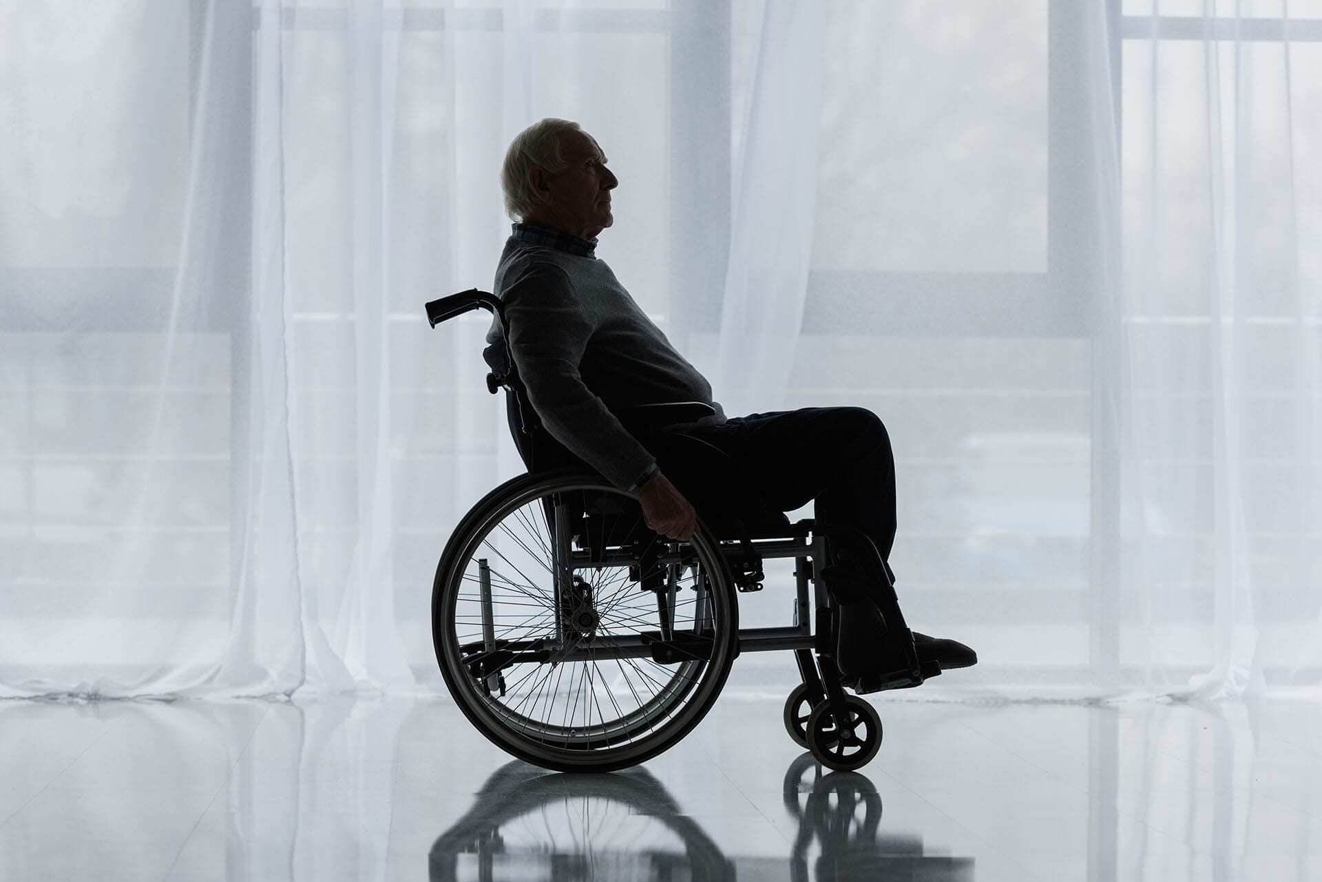 Senior in wheelchair in front of window