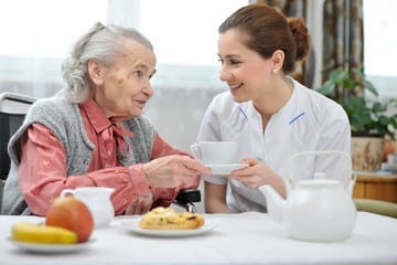 caregiver having tea with an elderly patient