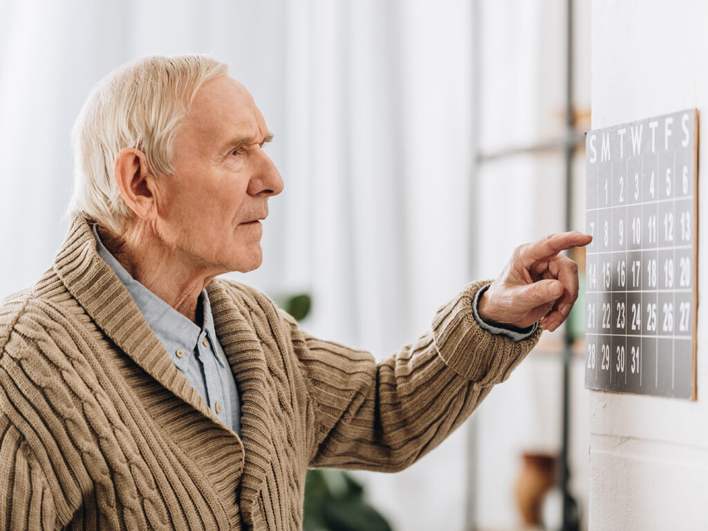 Elderly man reading a calendar.